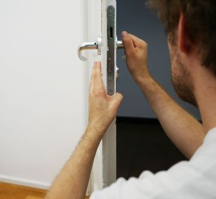 locksmith pulling on a door handle and insepcting a lock