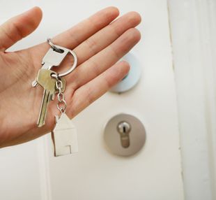 Keys in someones hand in front of a door